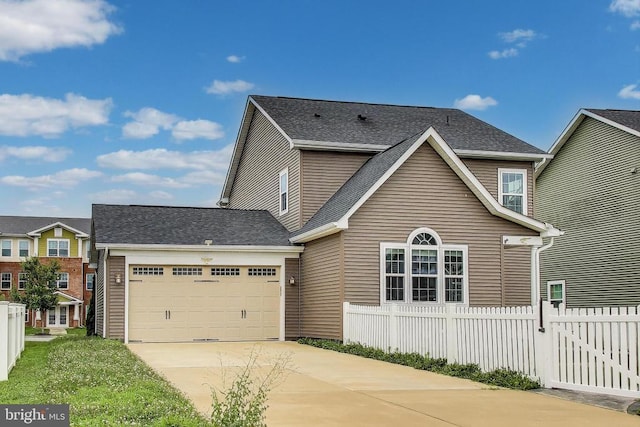 - traditional home with driveway, an attached garage, and a shingled roof