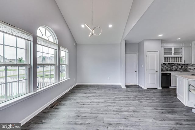  - kitchen with light countertops, vaulted ceiling, white cabinetry, wood finished floors, and dishwasher