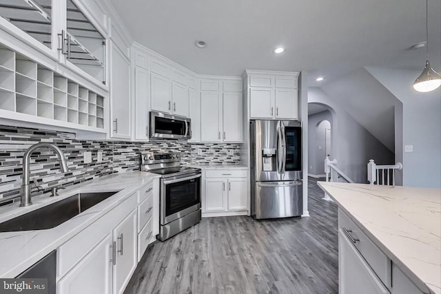  - kitchen featuring appliances with stainless steel finishes, white cabinets, arched walkways, open shelves, and tasteful backsplash