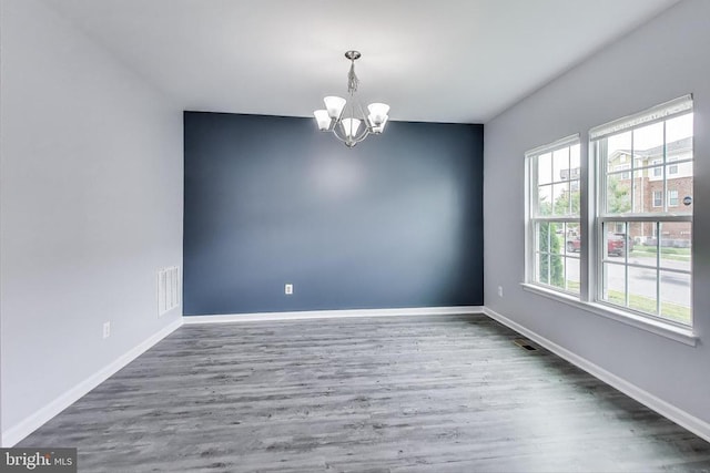  - spare room with a chandelier and wood finished floors