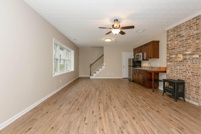 640 Greenwood St, Rockingham, VA 22801 - unfurnished living room featuring light wood finished floors, a ceiling fan, a wood stove, baseboards, and stairs