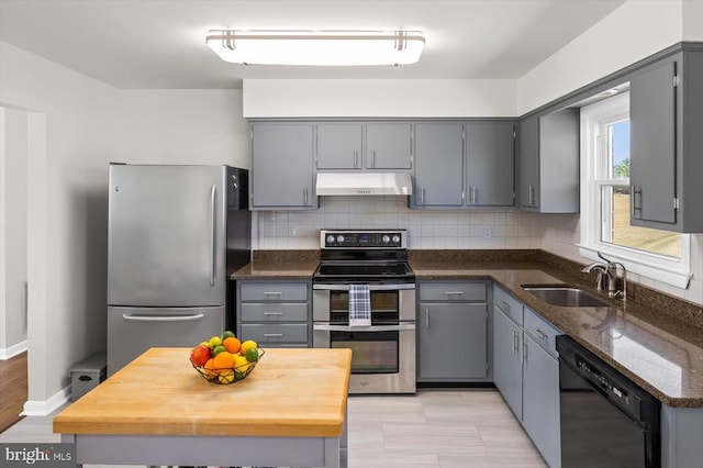 kitchen with a sink, appliances with stainless steel finishes, gray cabinets, and under cabinet range hood