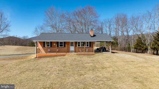 view of front of house with covered porch, an attached carport, a front yard, and dirt driveway