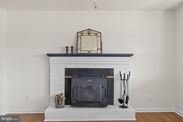 details featuring baseboards, wood finished floors, and a fireplace