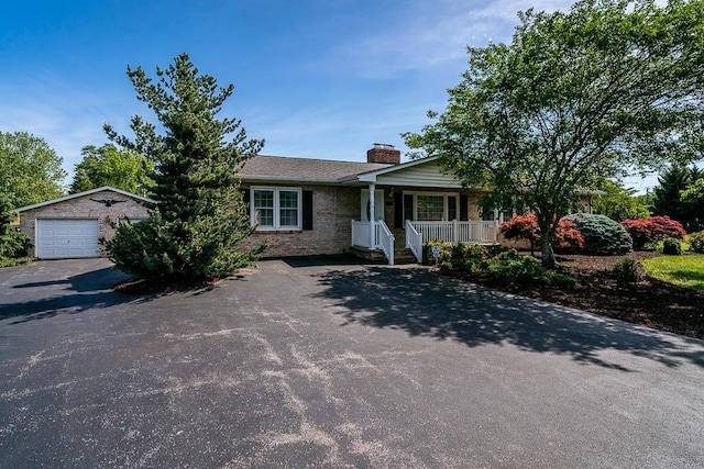 404 3rd St, Grottoes, VA 24441 - view of front facade featuring covered porch, a chimney, driveway, brick siding, and a garage