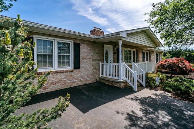404 3rd St, Grottoes, VA 24441 - view of front of house featuring a chimney, brick siding, and covered porch
