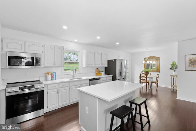 kitchen with appliances with stainless steel finishes, a sink, a kitchen breakfast bar, a chandelier, and white cabinets