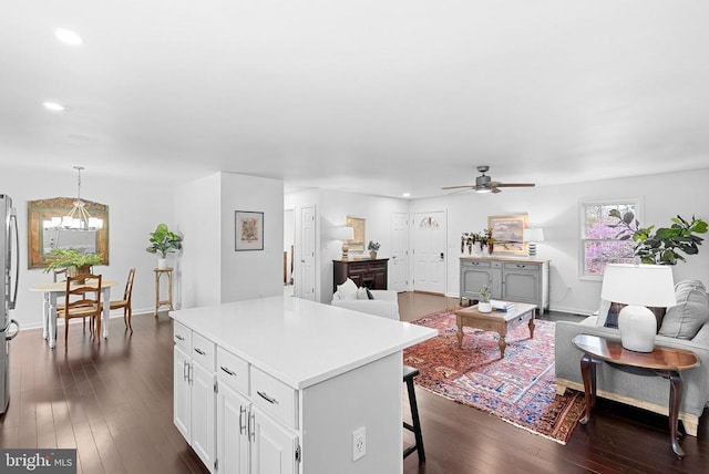 living area featuring a ceiling fan, recessed lighting, dark wood-style flooring, a chandelier, and baseboards