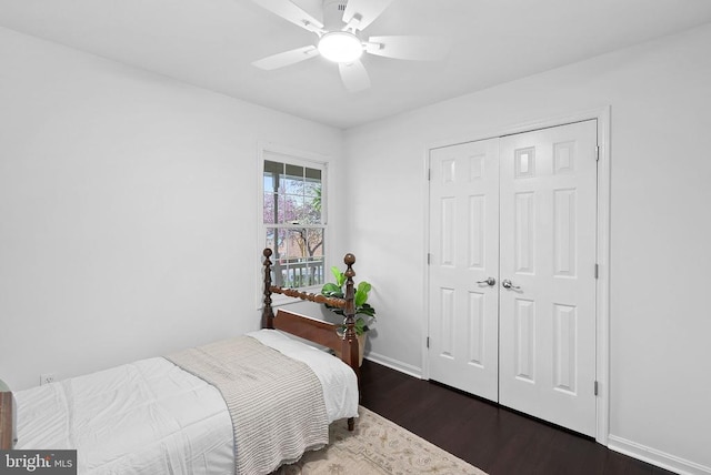 bedroom with dark wood finished floors, baseboards, a ceiling fan, and a closet