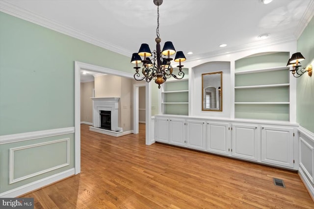 3905 Corbin Hall Ln, Fredericksburg, VA 22408 - unfurnished dining area with a chandelier, crown molding, a fireplace with raised hearth, light wood-type flooring, and built in features