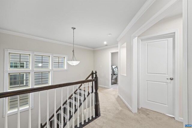 corridor with washer / clothes dryer, light colored carpet, an upstairs landing, crown molding, and baseboards