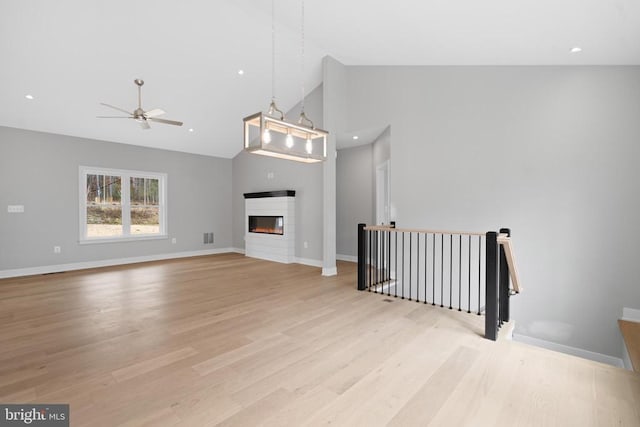 10643 Settle School Rd, Rixeyville, VA 22737 - unfurnished living room featuring a ceiling fan, baseboards, a glass covered fireplace, high vaulted ceiling, and light wood-type flooring