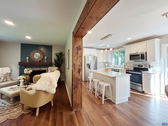 1203 Afton Mountain Rd, Afton, VA 22920 - kitchen with appliances with stainless steel finishes, tasteful backsplash, a breakfast bar, white cabinetry, and light wood finished floors