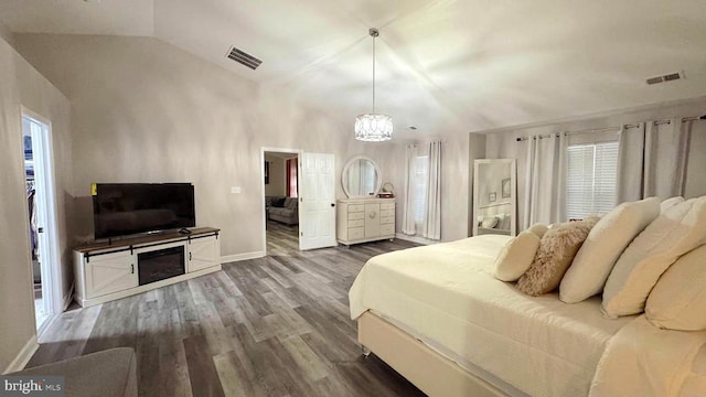 bedroom with vaulted ceiling, a walk in closet, an inviting chandelier, and hardwood / wood-style floors