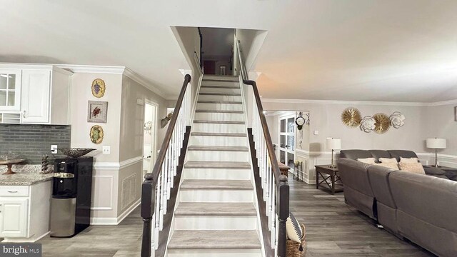 stairs featuring crown molding and hardwood / wood-style flooring