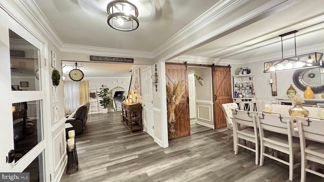 dining area with crown molding, a barn door, and dark wood-type flooring