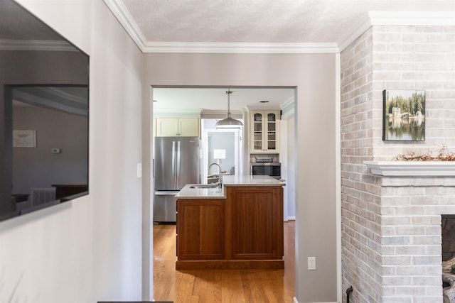 1014 22nd St E, Buena Vista, VA 24416 - kitchen with freestanding refrigerator, light wood finished floors, ornamental molding, a fireplace, and light countertops