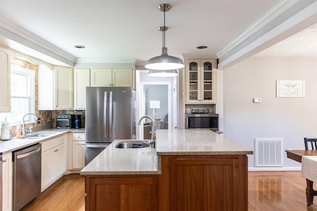 1014 22nd St E, Buena Vista, VA 24416 - kitchen with stainless steel appliances, a kitchen island with sink, tasteful backsplash, light wood finished floors, and crown molding
