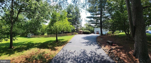  - surrounding community with driveway, a garage, and view of wooded area