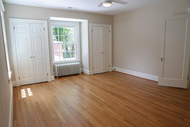 645 Cherry Ave, Waynesboro, VA 22980 - unfurnished bedroom featuring radiator, light wood-type flooring, baseboards, two closets, and ceiling fan