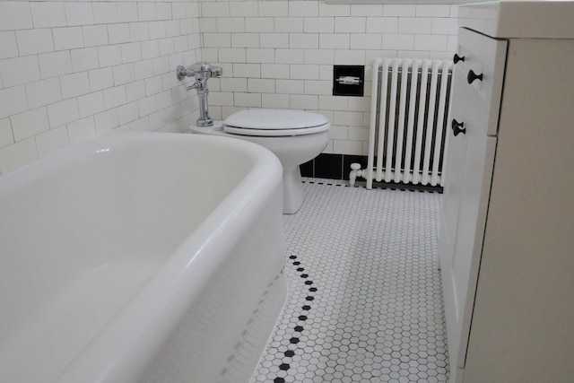 645 Cherry Ave, Waynesboro, VA 22980 - bathroom featuring radiator, tile walls, a soaking tub, and toilet
