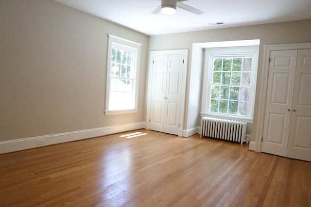645 Cherry Ave, Waynesboro, VA 22980 - unfurnished bedroom featuring radiator, light wood-style flooring, multiple windows, and multiple closets
