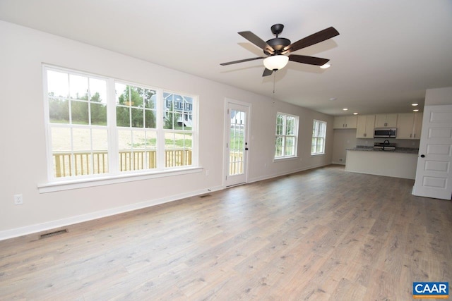 unfurnished living room featuring ceiling fan, baseboards, visible vents, and light wood-style floors