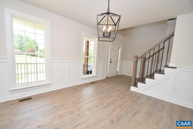 entrance foyer with stairs, an inviting chandelier, and a decorative wall