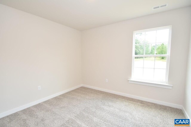 spare room with carpet, baseboards, and visible vents