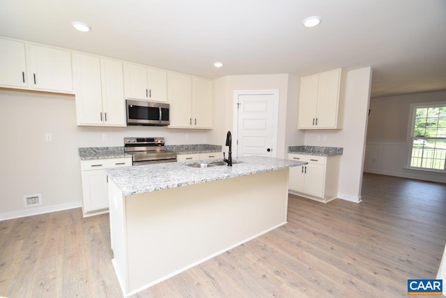 219 Riva Way, Palmyra, VA 22963 - kitchen featuring stainless steel appliances, a sink, light wood-style flooring, an island with sink, and light stone countertops
