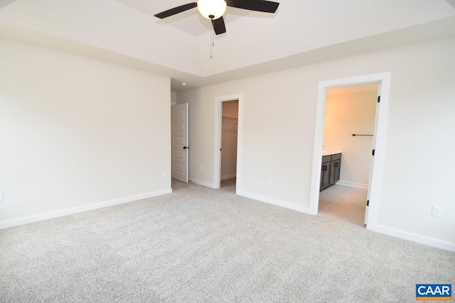 unfurnished bedroom featuring baseboards, light carpet, a closet, and a spacious closet
