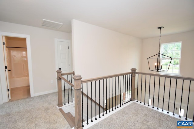 corridor featuring carpet flooring, an inviting chandelier, an upstairs landing, visible vents, and baseboards