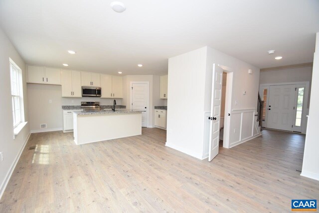 kitchen with a sink, light wood finished floors, stainless steel appliances, and white cabinets