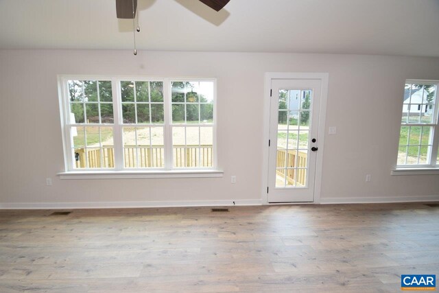 interior space with a ceiling fan, baseboards, visible vents, and wood finished floors