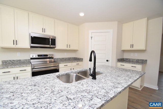 kitchen featuring a sink, stainless steel appliances, light stone counters, dark wood-style floors, and baseboards