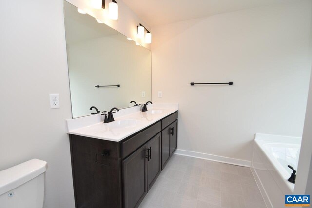 bathroom with a sink, double vanity, toilet, and baseboards