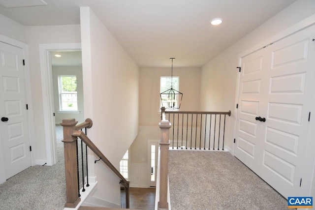 hallway with an upstairs landing, an inviting chandelier, recessed lighting, and carpet