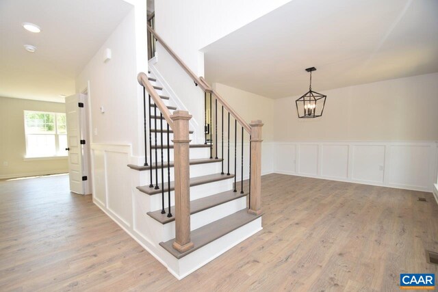 219 Riva Way, Palmyra, VA 22963 - stairway featuring wood finished floors, a chandelier, a decorative wall, and a wainscoted wall