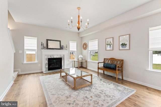 living room with a chandelier, light wood finished floors, and baseboards