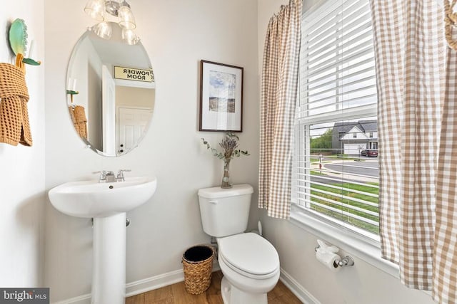 bathroom with toilet, wood finished floors, baseboards, and a sink