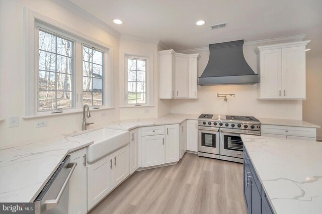  - kitchen featuring custom range hood, appliances with stainless steel finishes, a sink, white cabinets, and crown molding