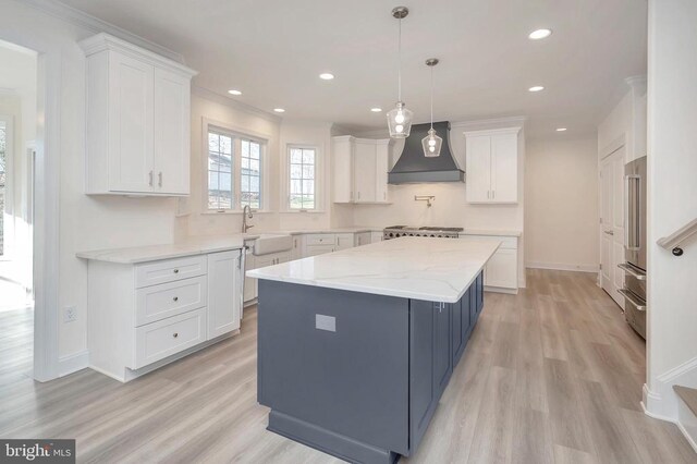  - kitchen featuring premium range hood, a sink, recessed lighting, white cabinetry, and light wood finished floors