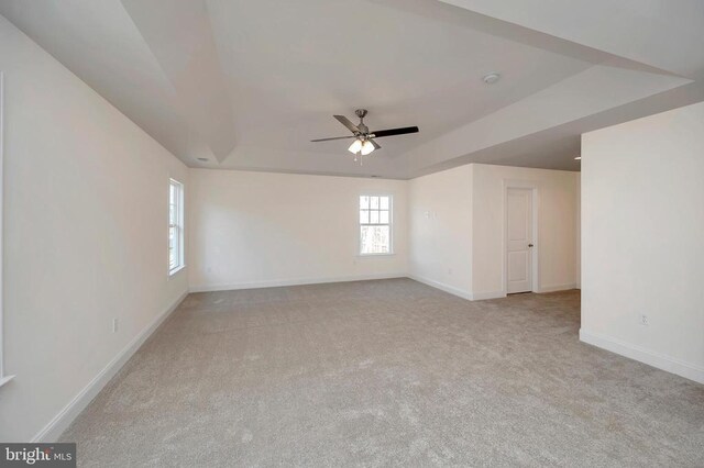  - unfurnished room featuring a ceiling fan, carpet floors, baseboards, and a raised ceiling