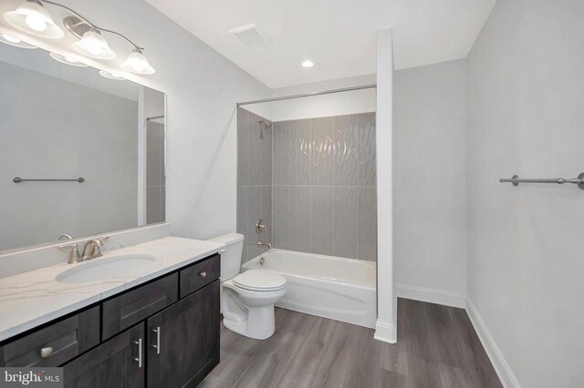  - bathroom with wood finished floors, toilet, vanity, shower / tub combination, and baseboards