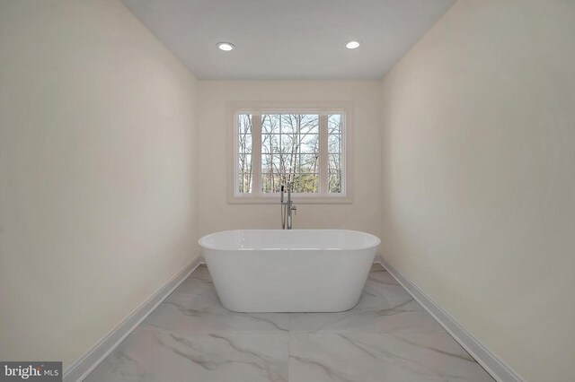  - full bath with marble look tile flooring, a freestanding tub, baseboards, and recessed lighting