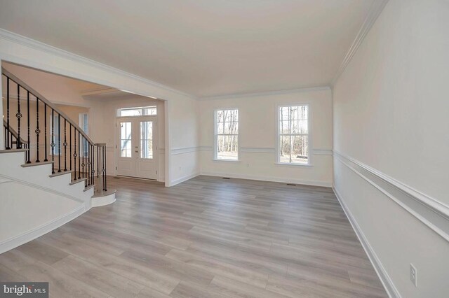  - unfurnished living room featuring ornamental molding, plenty of natural light, stairway, wood finished floors, and baseboards
