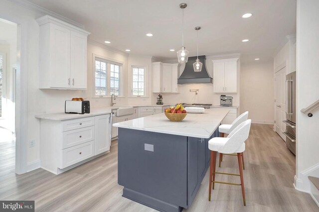  - kitchen featuring custom exhaust hood, a sink, light wood finished floors, recessed lighting, and white cabinetry