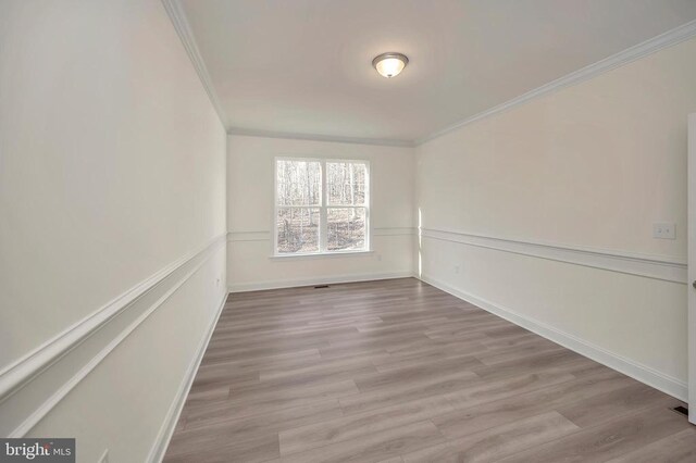  - empty room with ornamental molding, wood finished floors, and baseboards