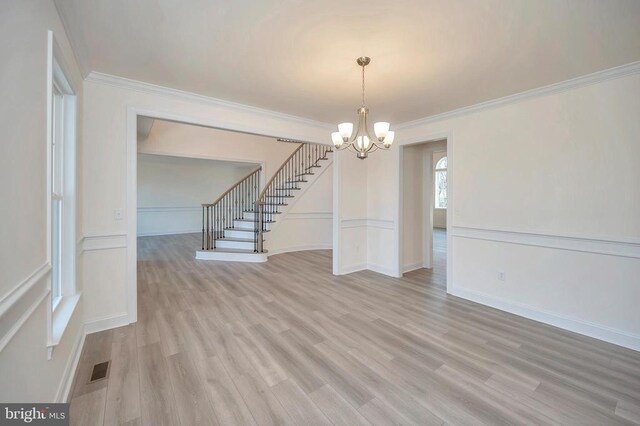  - unfurnished dining area with a chandelier, light wood-style flooring, crown molding, stairs, and baseboards