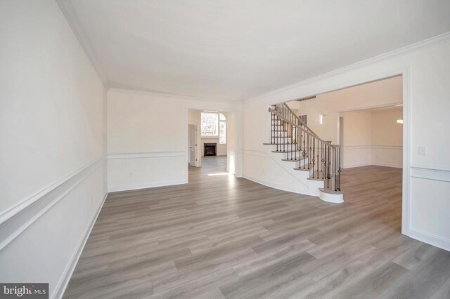  - unfurnished living room featuring crown molding, stairs, a fireplace, wood finished floors, and baseboards